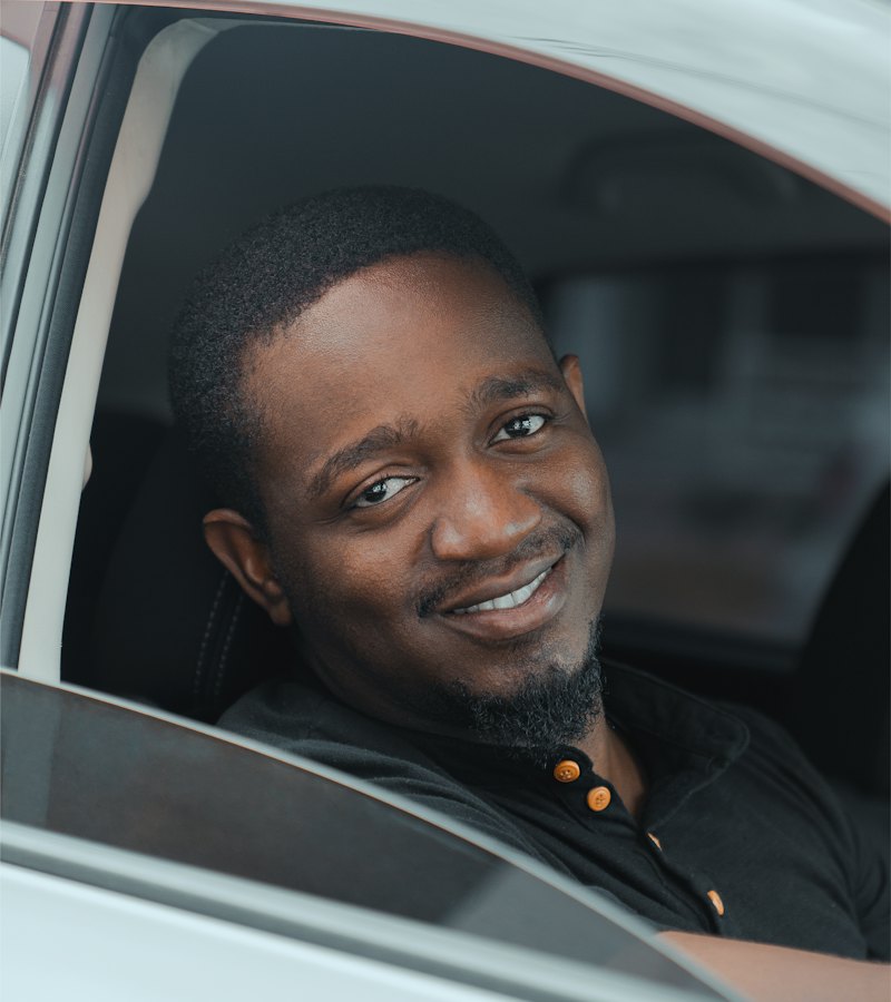 A smiling driver sitting at the wheel of his car
