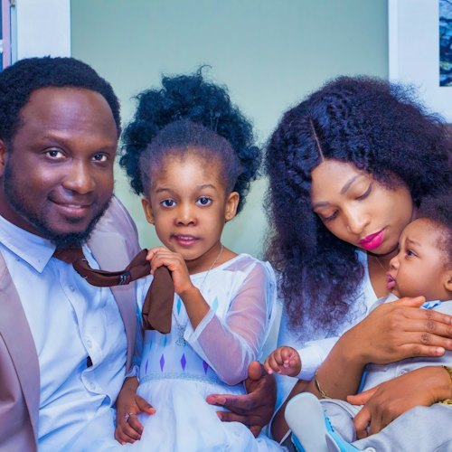 A smiling family of four, parents with their two young children