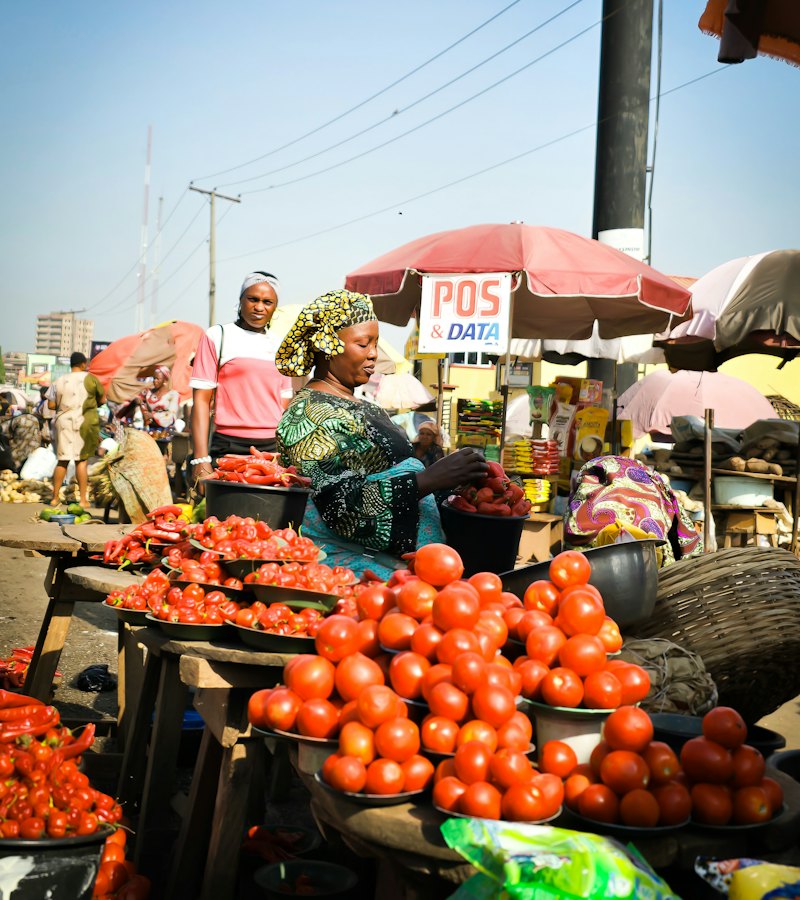 A marketeer selling tomatoes and vegetables at a busy street market
